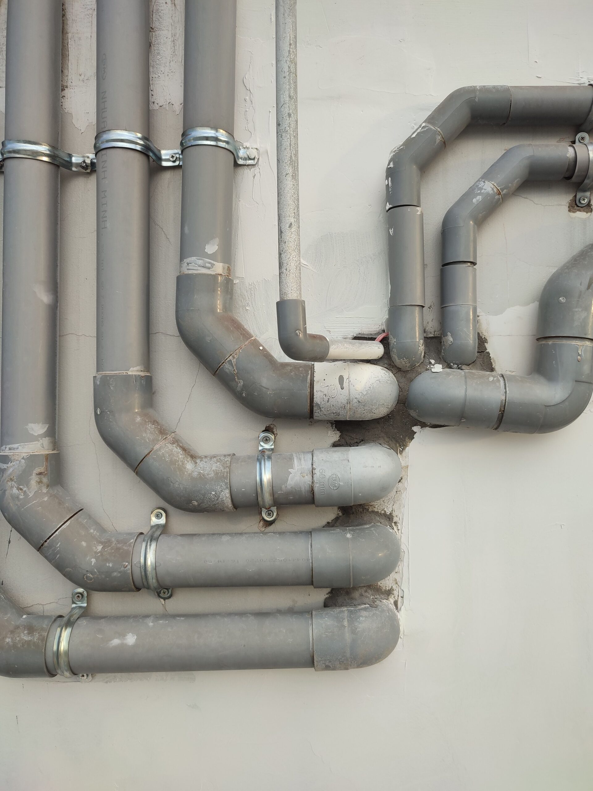 Impressum Close-up of interconnected gray metal pipes on an outdoor wall showcasing industrial design.